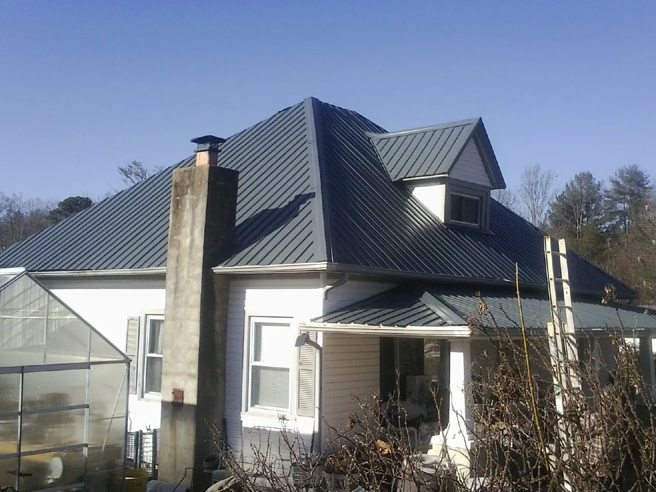 Dark blue standing seam metal roof on a white farmhouse with dormer — Slate & Tile Roof Repair by Roofing Brothers in Chiloquin