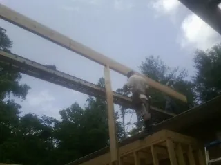 Carpenter setting a ridge beam over a new addition frame — Ice Dam Removal by Roofing Brothers in Chiloquin