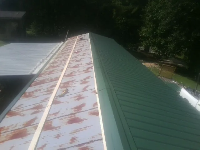 Old rusted panels beside newly installed green metal roofing — Wind Damage Roof Repair by Roofing Brothers in Chiloquin