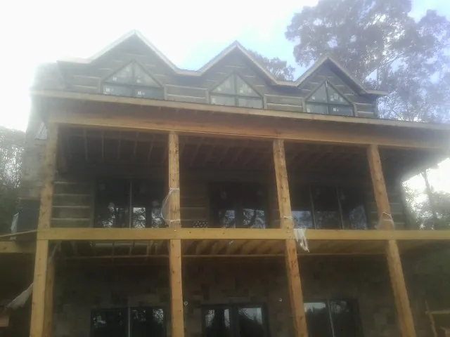 Dormers and porch framing on a large log home under construction — Roof Coating work by our crew in Chiloquin