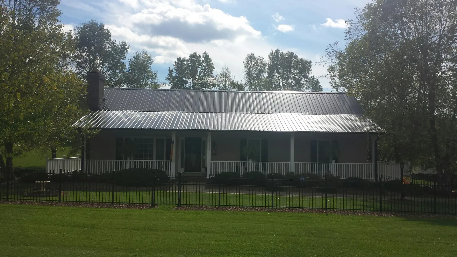 Gray metal roof on a brick ranch with a full width front porch — Gutter Guard Installation work by our crew in Chiloquin