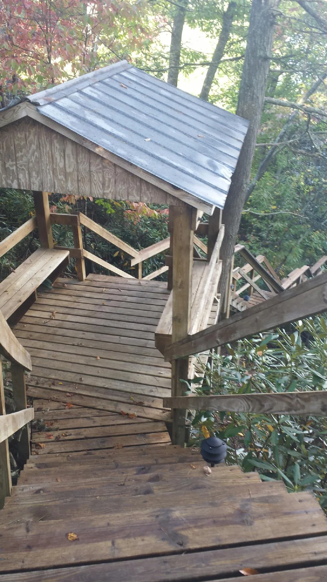 Metal roofed shelter over wooden steps on a wooded walkway — Skylight Repair & Installation work by our crew in Chiloquin